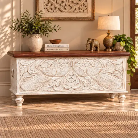 Hand-carved mango wood storage cabinet with two closed floral-carved doors, white finish and gold-tipped legs displayed in a warm interior.