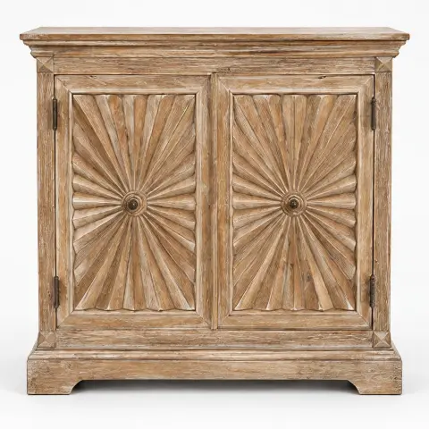Hand-carved sunburst wooden storage cabinet with two decorative radial-carved doors, layered top moulding, distressed natural finish and plinth base in a styled interior.