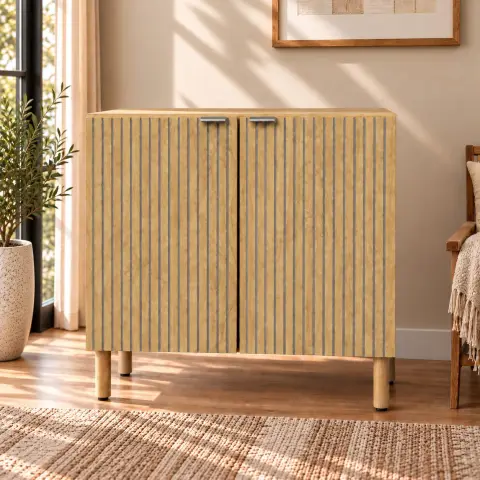 Handcrafted wooden sideboard cabinet with two textured doors, silver-tone handles, raised wooden legs and vertical decorative detailing in a warm interior setting