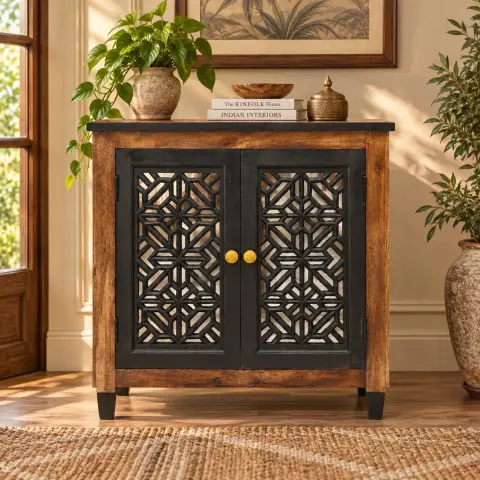 Closed front lifestyle view of a mango wood storage cabinet with two black geometric lattice doors, round brass-tone knobs, natural wood frame and black tapered legs.